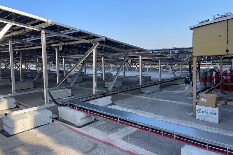 קונסטרוקציה גבוהה ופאנלים סולארים על גג בטון עם תעלות חיווט למערכת סולארית מסחרית